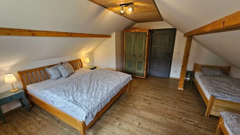 2 postele medzi ktorými sú drevené dvere a skriňa